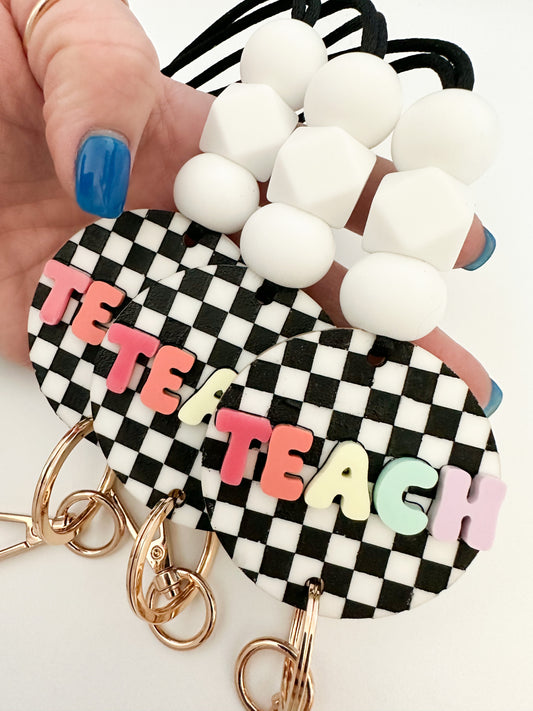 black + white checkerboard with multi-color TEACH lanyard