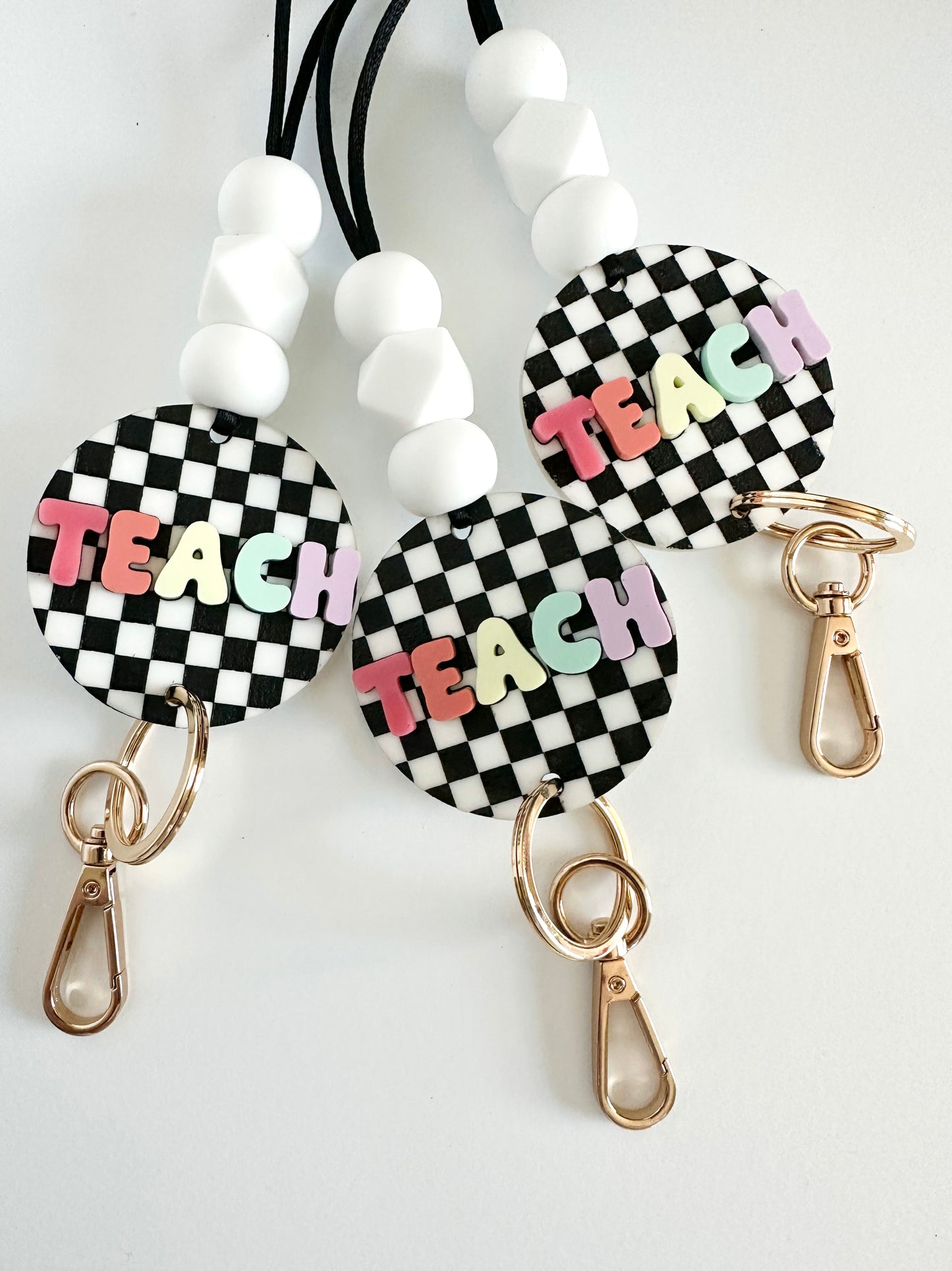 black + white checkerboard with multi-color TEACH lanyard