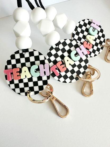 black + white checkerboard with multi-color TEACH lanyard